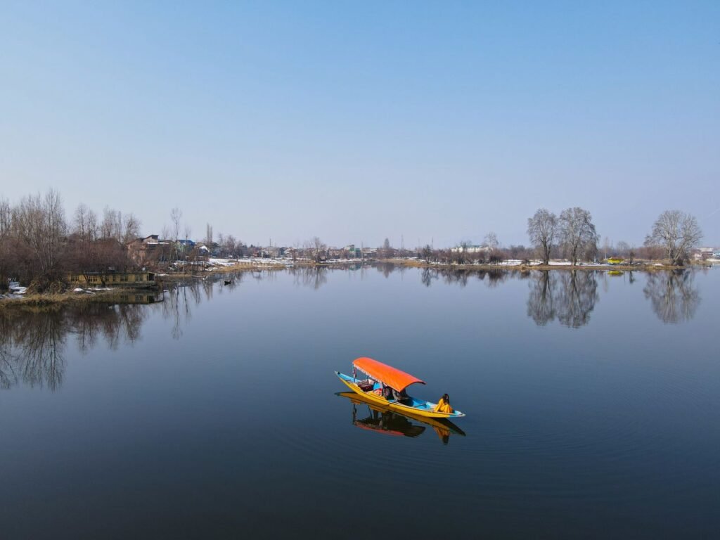 Peaceful boat ride on Dal Lake in Srinagar, with stunning reflections and a clear blue sky.